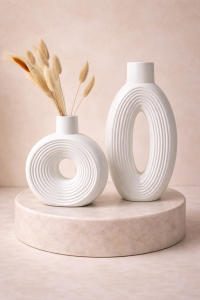 Modern white ribbed ceramic vase set on a beige marble pedestal with dried bunny tail stems