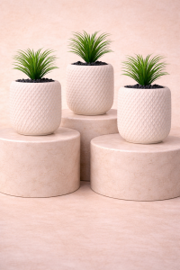 Three mini faux plants in white textured pots on beige pedestal background