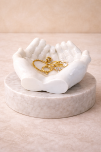 White hand trinket dish jewelry holder on marble pedestal holding gold jewelry